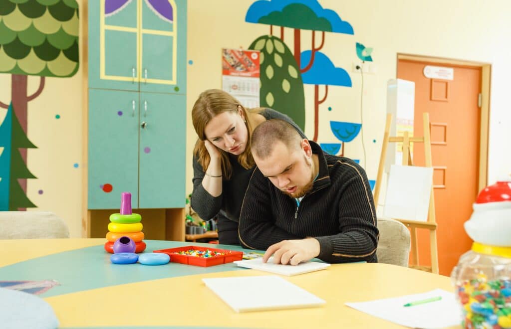 A Psychologist Is Engaged With An Adult Autistic Man In The Office.