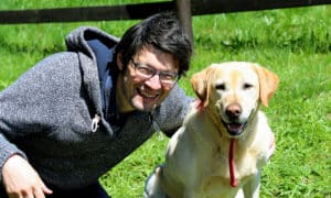 man with blacks hair smiling with his labrador dog