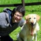 man with blacks hair smiling with his labrador dog